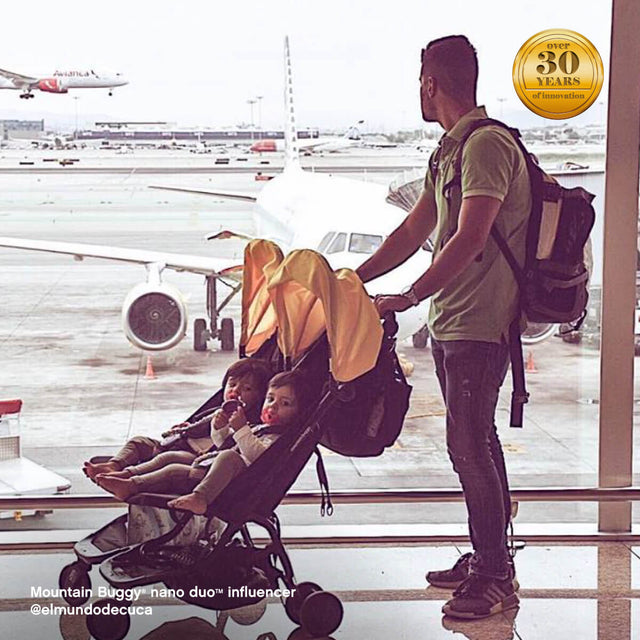 dad with two toddlers in nano duo pram, waiting at the airport - Mountain Buggy nano duo™ influencer @elmundodecuca