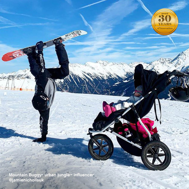 active family visiting snowy mountains as toddler keeps warm riding in mountain buggy urban jungle all-terrain pram with sleeping bag - urban jungle™ influencer @jamienichollsuk